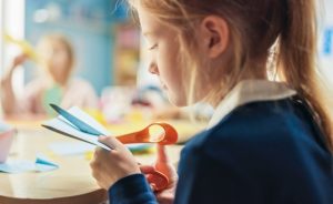A young girl cutting paper with scissors.