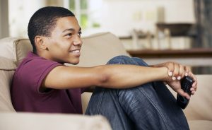 Teenager watching TV sitting on couch.