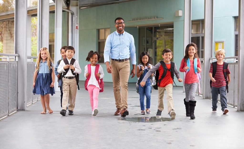 Male teacher walking together with children.