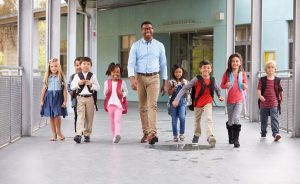 Male teacher walking together with children.