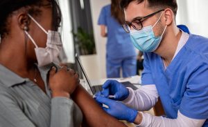 Male nurse giving a shot to a female patient.