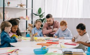 Young male teacher with children working at a table.