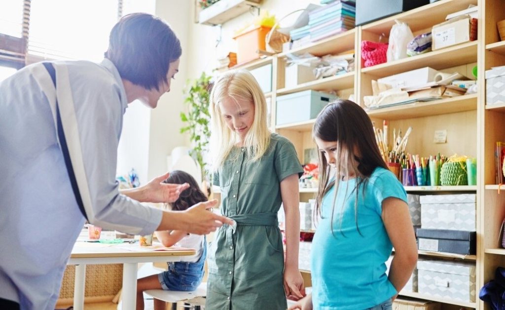 A teacher helps students in an art room.