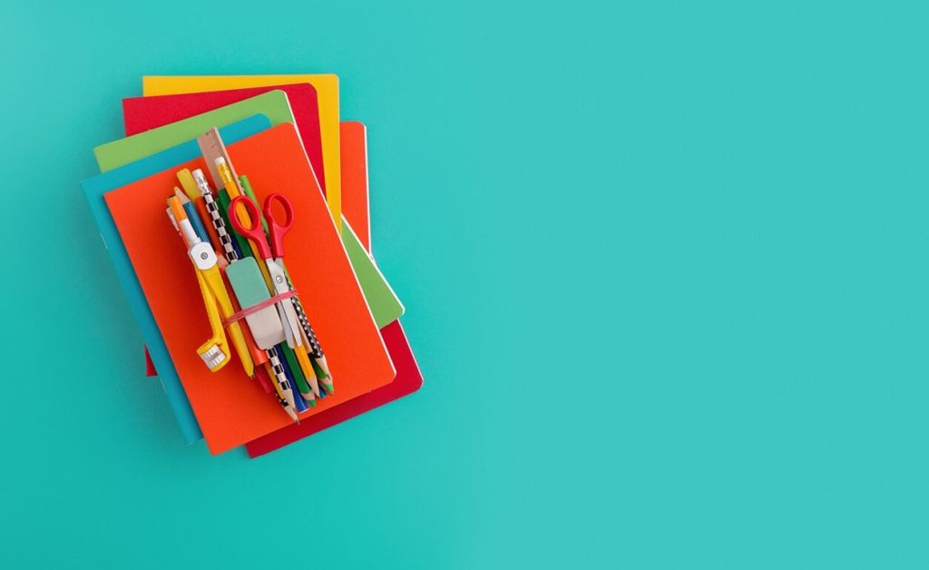Stack of colorful notebooks and school supplies.