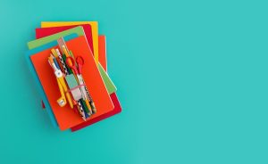 Stack of colorful notebooks and school supplies.