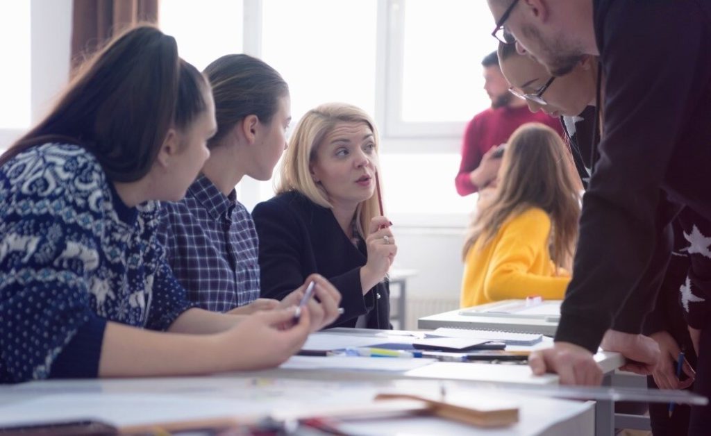 A teacher working with a group of students at a table.