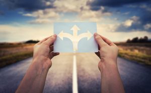 Hands holding a paper with arrows on a road background.