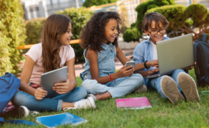 Young students using technology while sitting outside