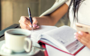 Female writing in journal during her morning coffee.