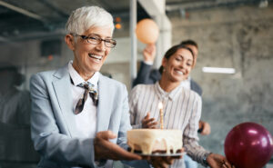 Female office leader carrying birthday cake in celebration