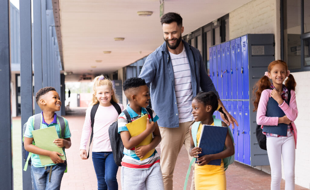 Male school administrator interacting with students in hallway