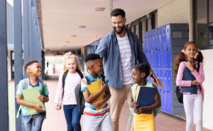 Male school administrator interacting with students in hallway