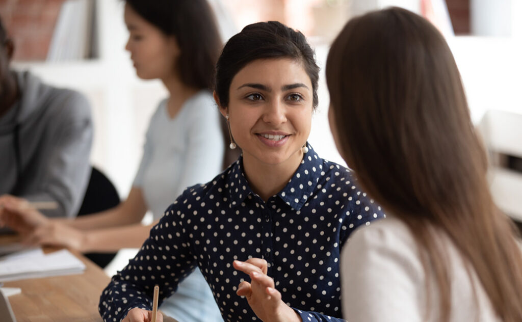 Two female students talking in classroom.