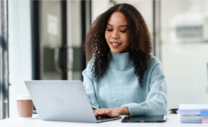 Woman smiles as she works from her laptop in a business environment